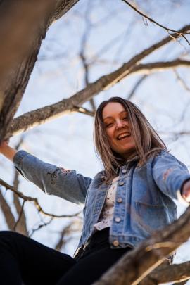 Young woman climbing tree and laughing 