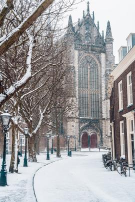 A snowy day in Leiden, the Netherlands, with the Hooglandse Kerk in the back and an empty street in the front.