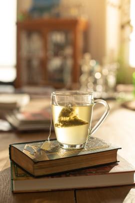 a steaming cup of herbal tea perched on a pile of vintage books