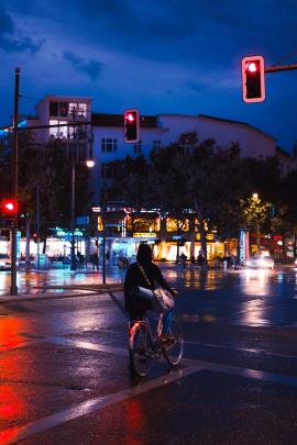 Some girl on a bike waiting at the traffic light in Berlin on a rainy evening.